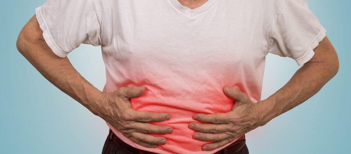 Stomach ache, man placing hands on the abdomen isolated on light blue background