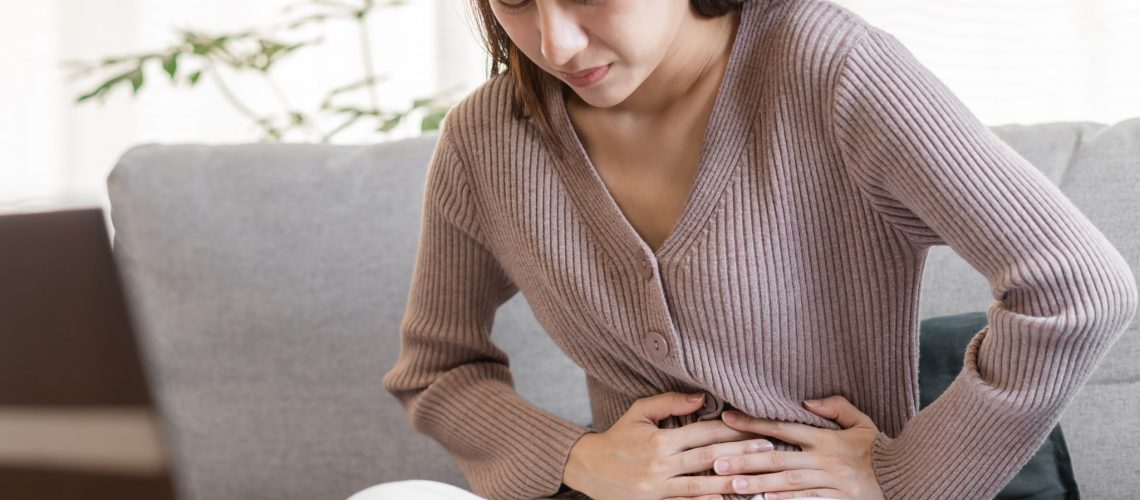 Flatulence young asian woman, girl hand in stomach ache, suffer from food poisoning, abdominal pain and colon problem, gastritis or diarrhoea. Patient belly, abdomen or inflammation, concept.