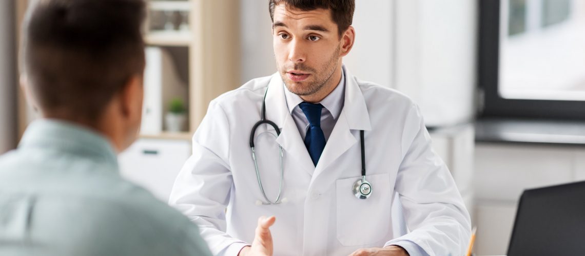 medicine, healthcare and people concept - doctor talking to male patient at medical office in hospital